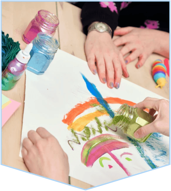 Hands collaborating on a colorful abstract painting with paint jars